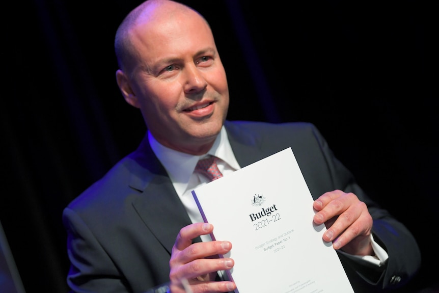 a man smiling and holding a white paper