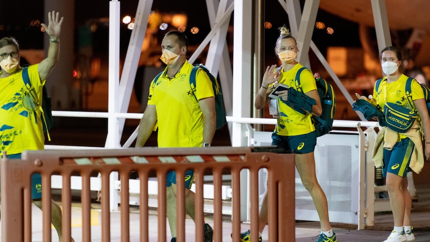Four Olympic athletes wave to the cameras as they arrive at Darwin Airport.