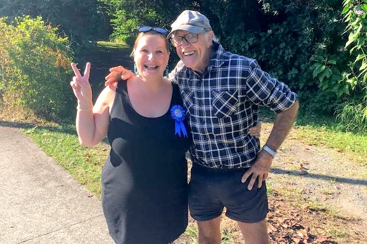 woman gives peace sign at camera with an elderly man