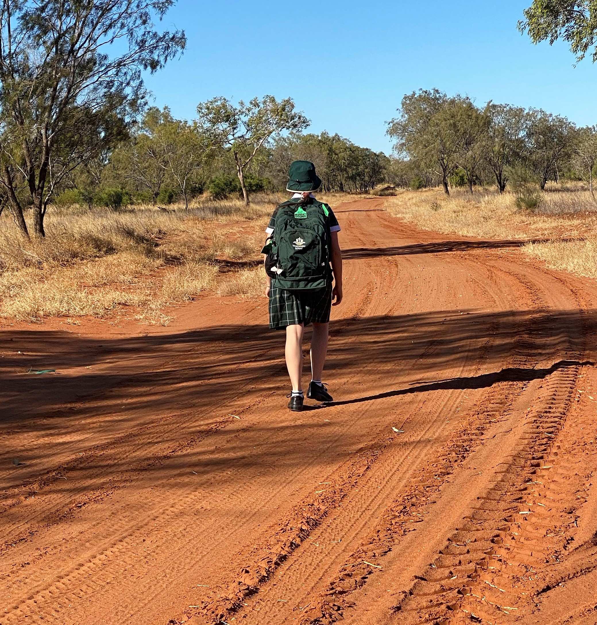 A schoolgirl from a remote region walks down a country road with her school gear.