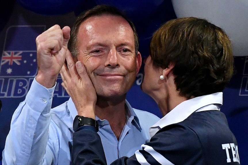 Tony Abbott with his fist in the air, with his wife Margie by his side