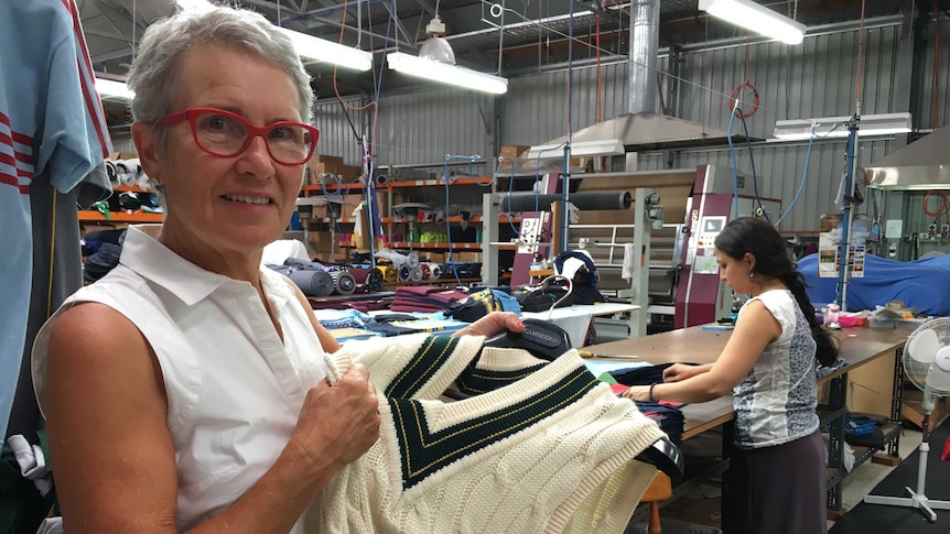 Lady stands in wool factory with Australian cricket jumper.