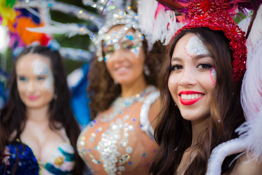 A group of women wearing costumes smile as they pose for a photograph.