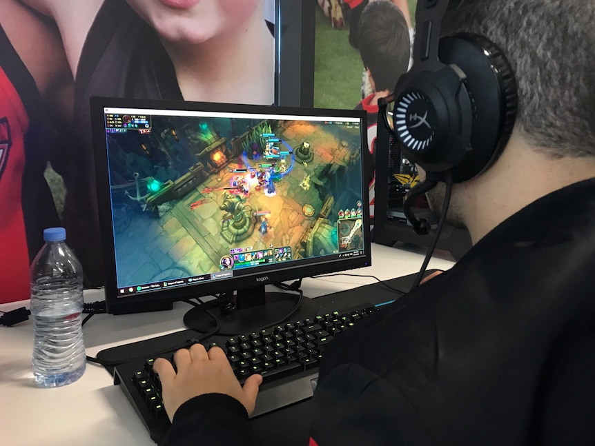 An e-Sports player sits in front of a screen playing League of Legends.