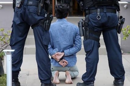A man kneels as police watch on.