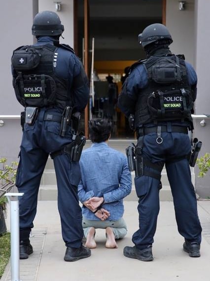 A man kneels as police watch on.