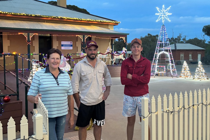 Three people stand in front of a light display. A woman, a man and a teenage boy. 