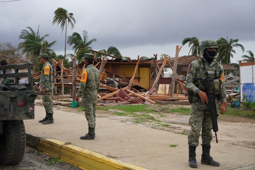 Żołnierze stojący przed zniszczonym domem
