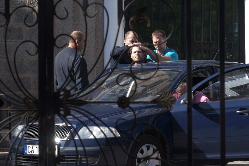 Men press down on Jock Palfreeman's head to lower him into a car.