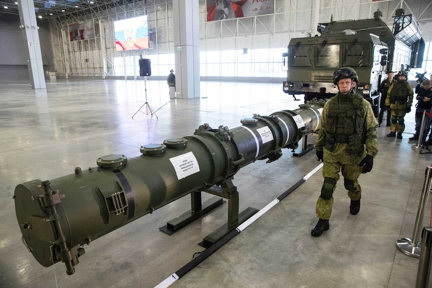 A Russian military officer walks past the 9M729 land-based cruise missile on display with its launcher