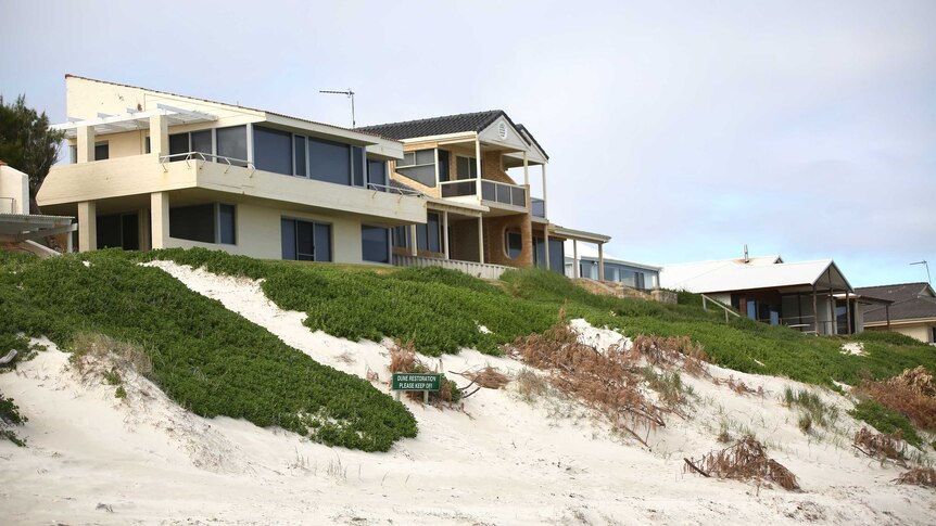 A row of houses perched above a beach.
