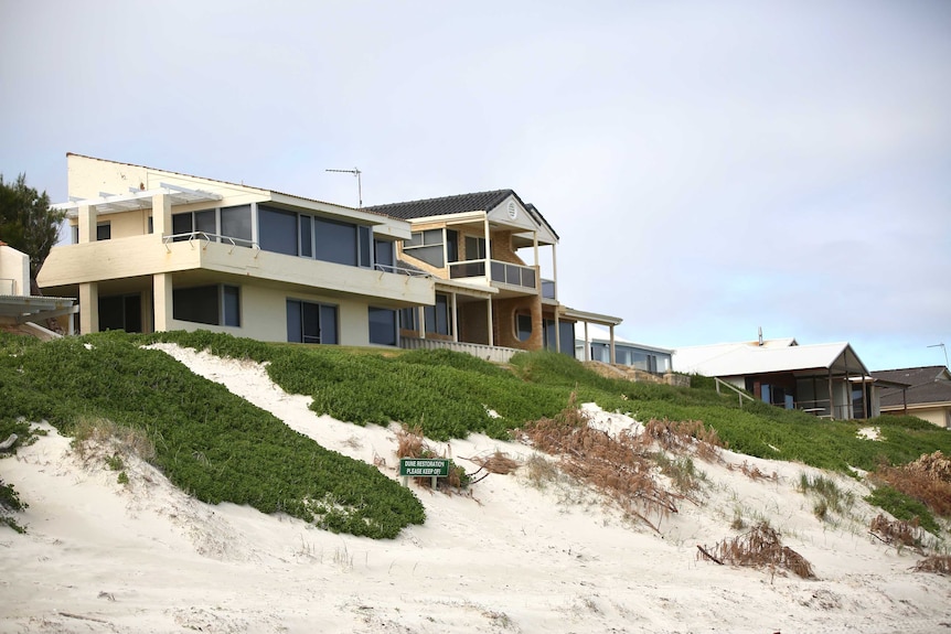 A row of houses perched above a beach.