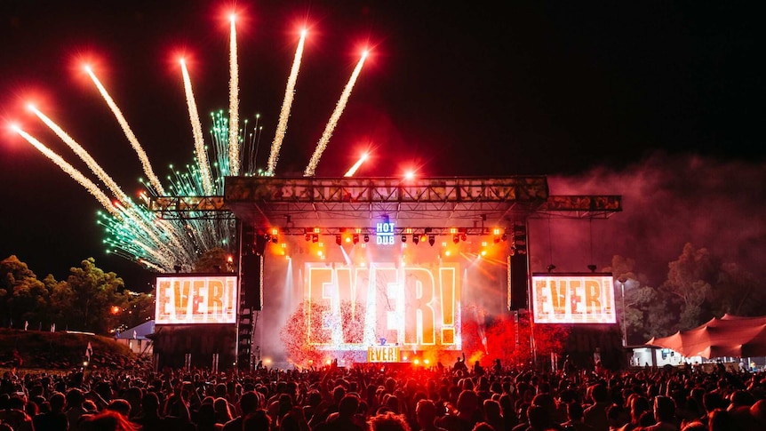 Fireworks go off behind a festival stage saying 'EVER!' on giant screens, promoting Sydney's NYE On The Park festival
