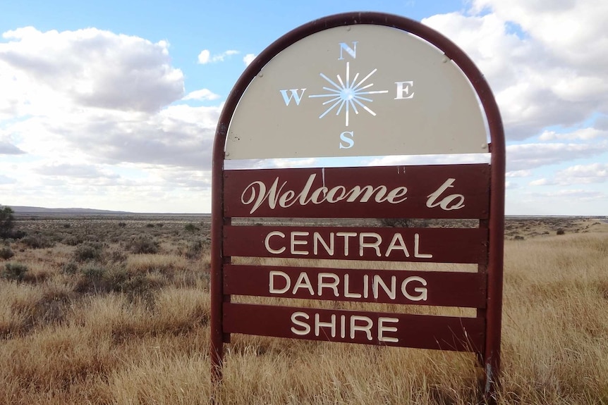 A sign with the words 'welcome to Central Darling Shire' in an expanse of grass and shrubs.