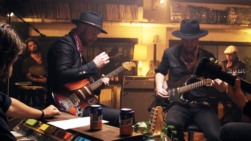 Several members of band The Counterfeit play their guitars in a moody recording studio. 