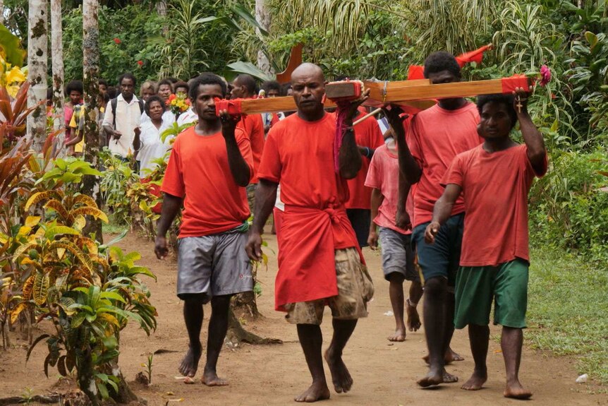 Villagers carry a crucifix to a Catholic prayer meeting for Sean Dorney in Tulu.