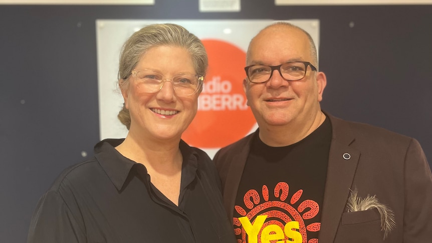 Two people smiling in front of the ABC logo, one wearing a 'yes' shirt.