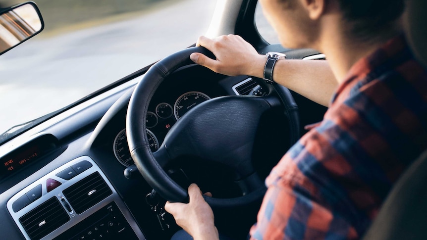 A man holds a steering wheel in a car.