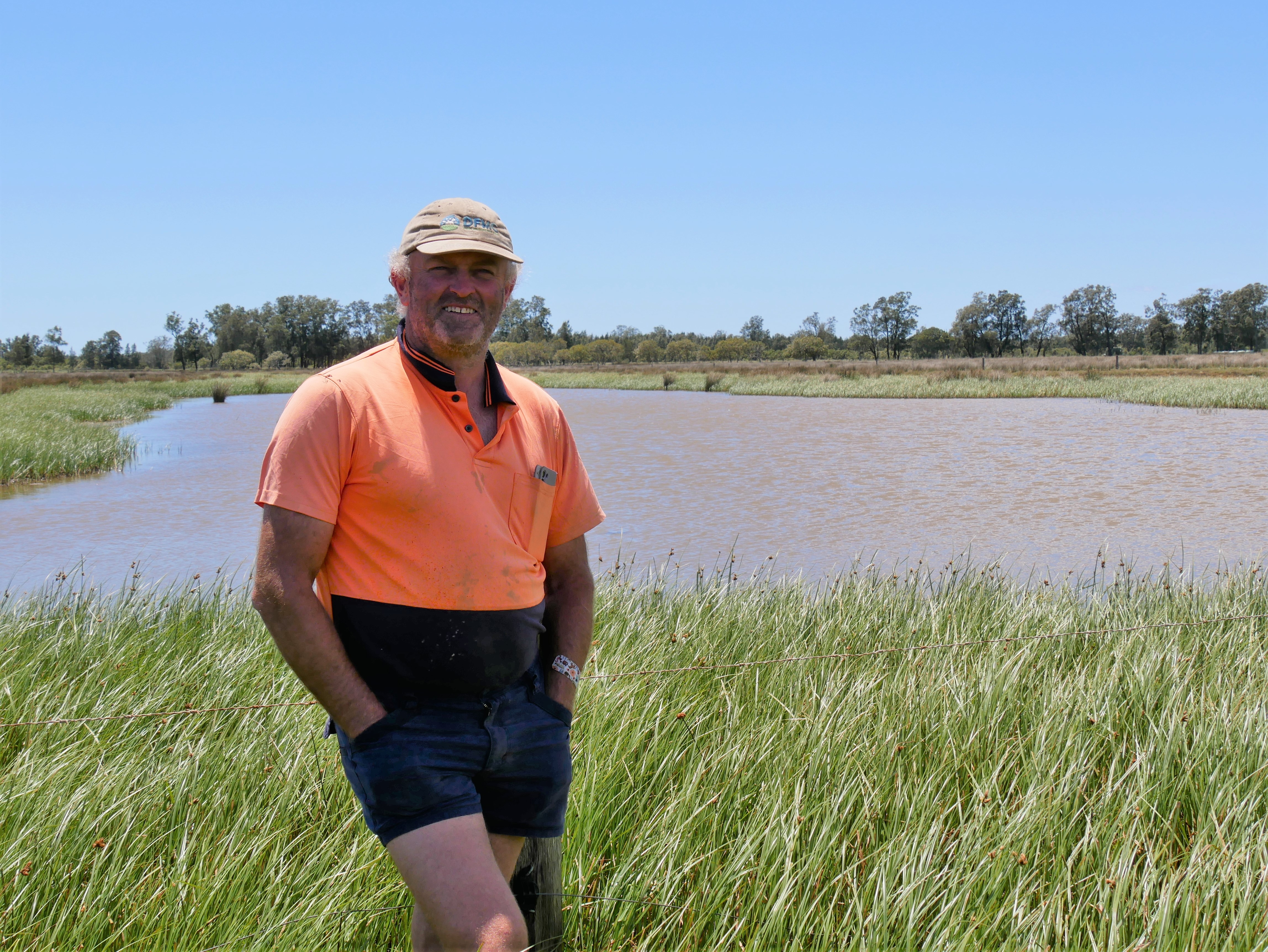 man standing in front of fenced wetland