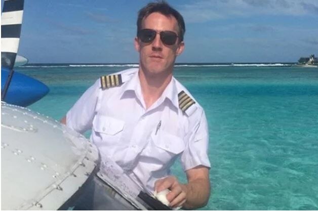 a plane pilot wearing sunglasses standing next to a plane in front of the water
