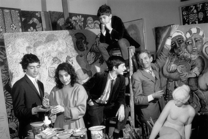 A black and white photograph of the artist Mirka Mora in her busy artists studio in 1967