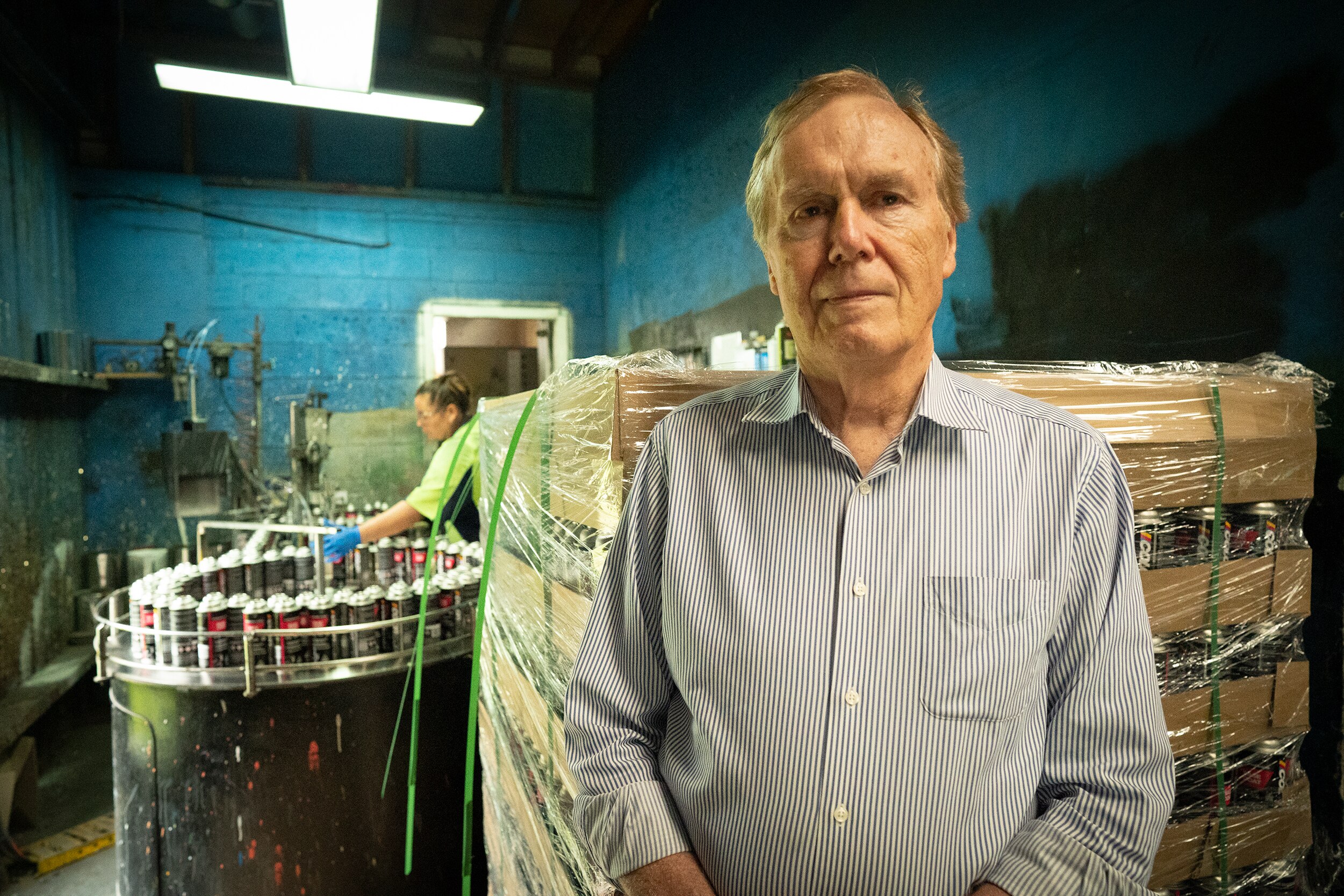 A man stands in a factory where an employee is manufacturing paint.