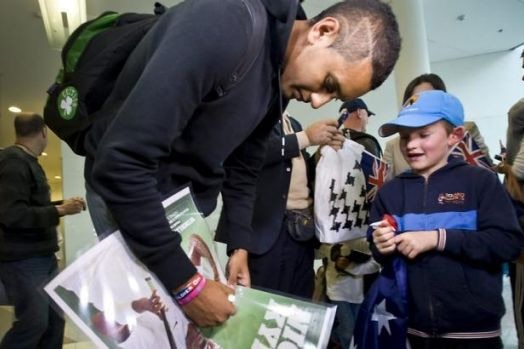 Nick Kyrgios signs an autograph for a young fan.