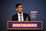 Sunak speaks in front of a lectern emblazoned with the slogan 'stop the boats'