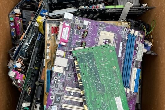 A box full of different-coloured motherboards and computer chips. 