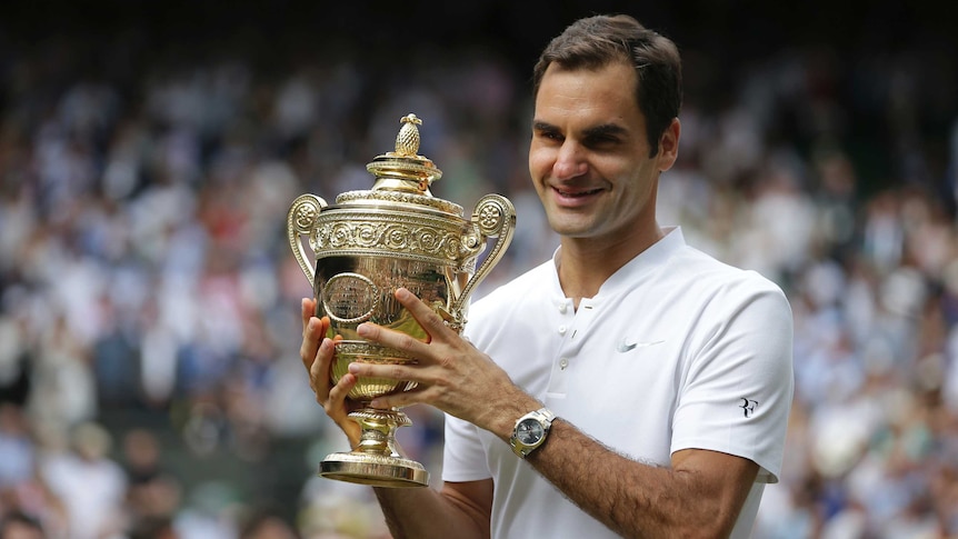 Roger Federer celebrates with the trophy after winning the Wimbledon title