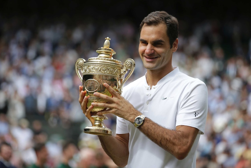 Roger Federer celebrates with the trophy after winning the Wimbledon title