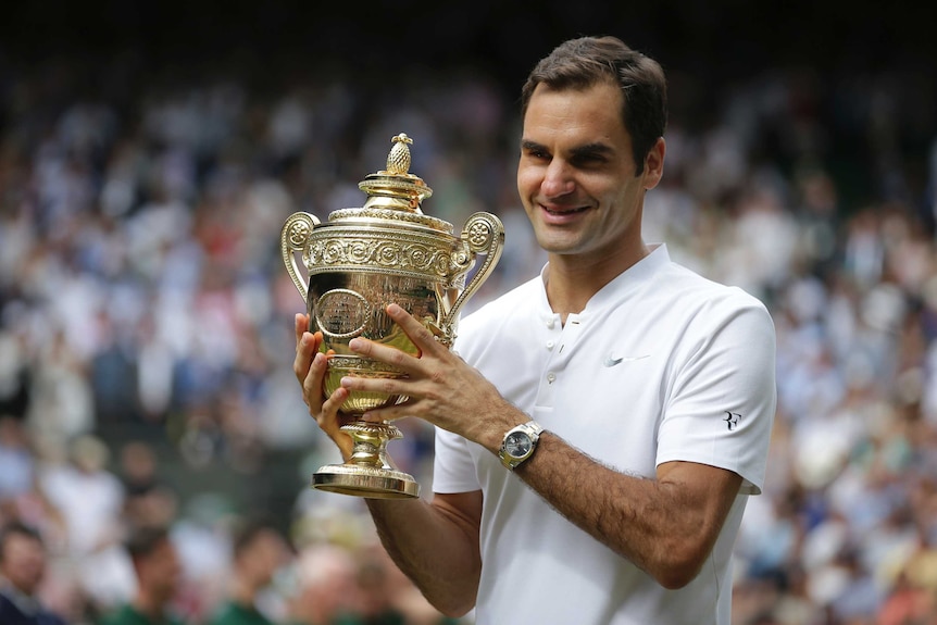 Roger Federer celebrates with the trophy after winning the Wimbledon title