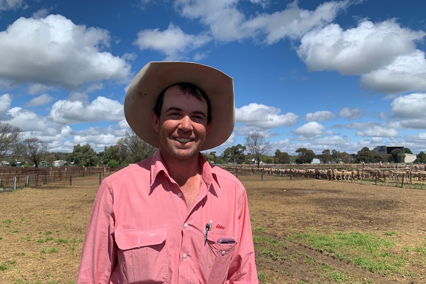 A man in a pink Elders shirt in front of the saleyards. 