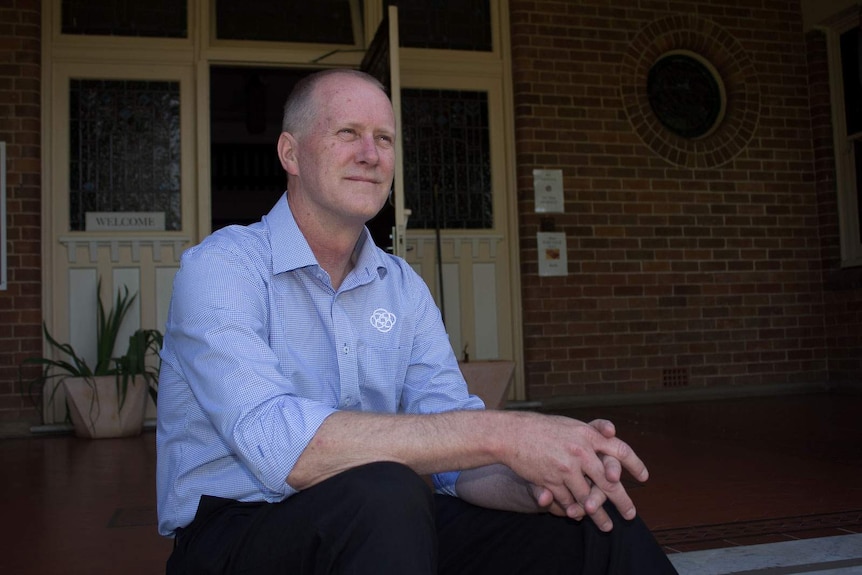 A man sits on the steps of an old building