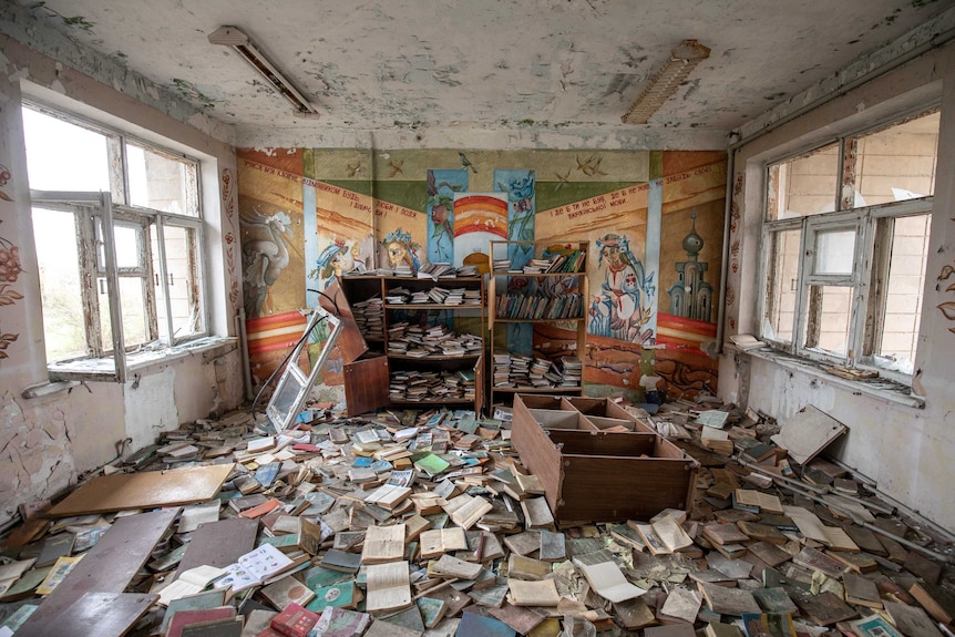 Books are strewn across the floor and cupboards upturned in an abandoned classroom.