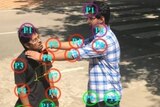 A drone image shows two men in a fighting position, with coloured circles around the points of contact.