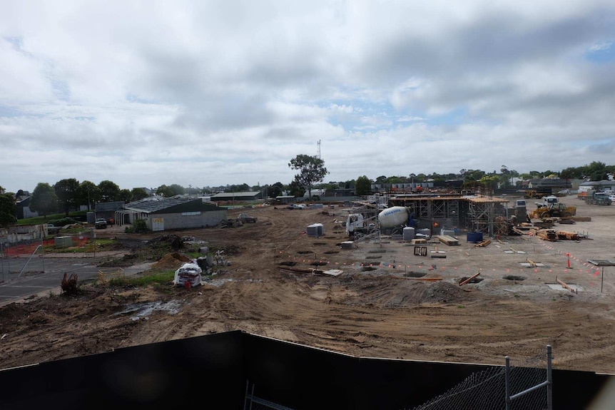 A photo of a construction site of building materials, a skeleton structure of a building and cement truck taken from a height