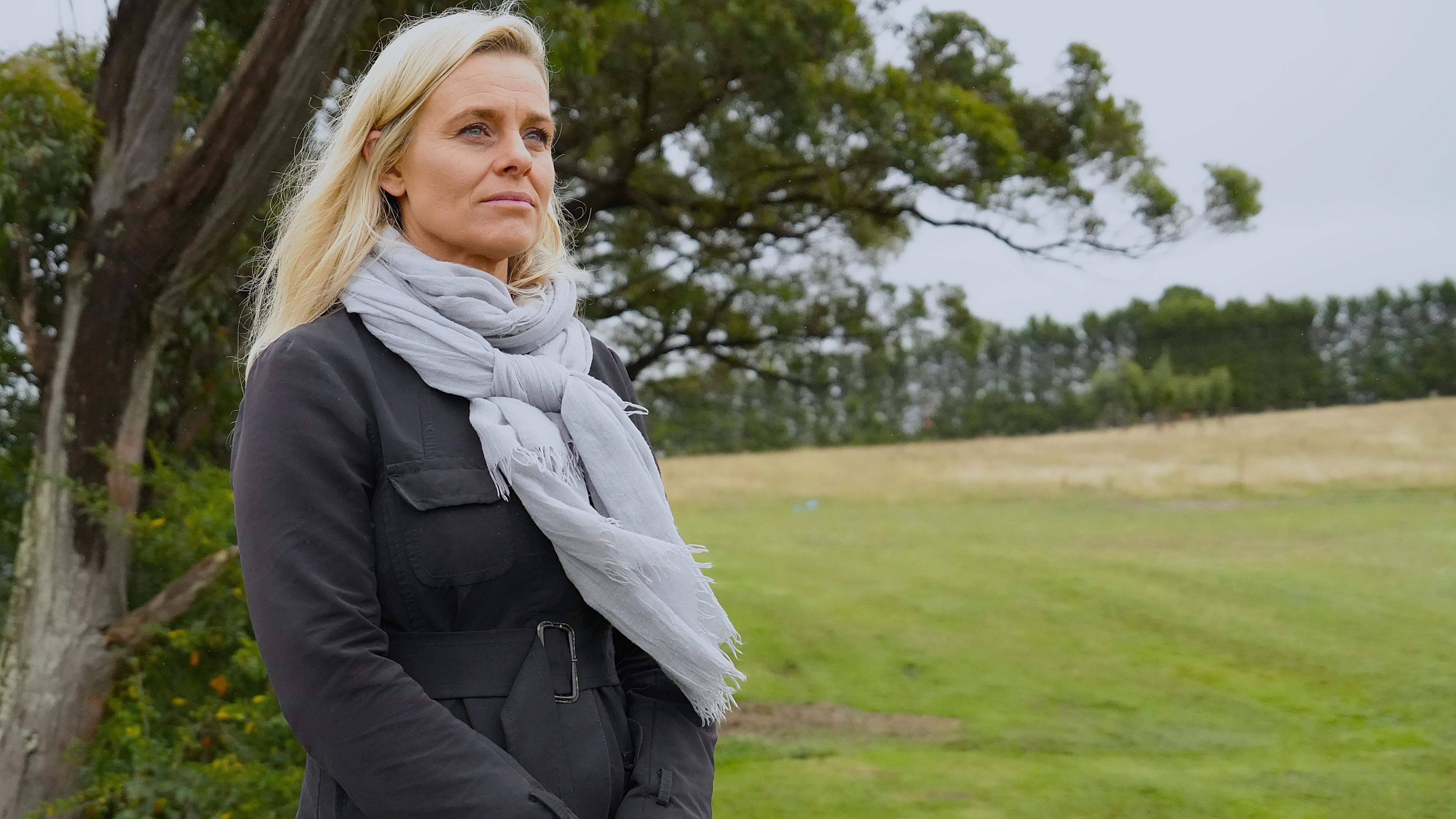 woman in winter gear looks over a green field