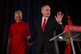 Bill Shorten waves to the crowd, supported by his wife Chloe