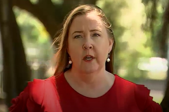 Woman in red top stands outside