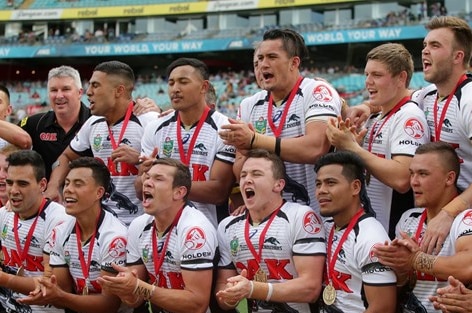 A team of rugby league players clap and shout.