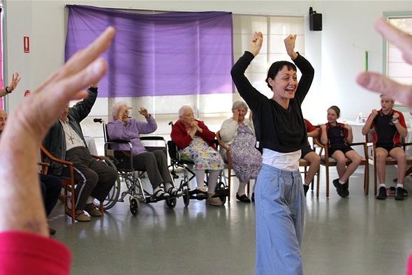 A dance instructor leads a group of elderly people and school students in some low impact dance moves.