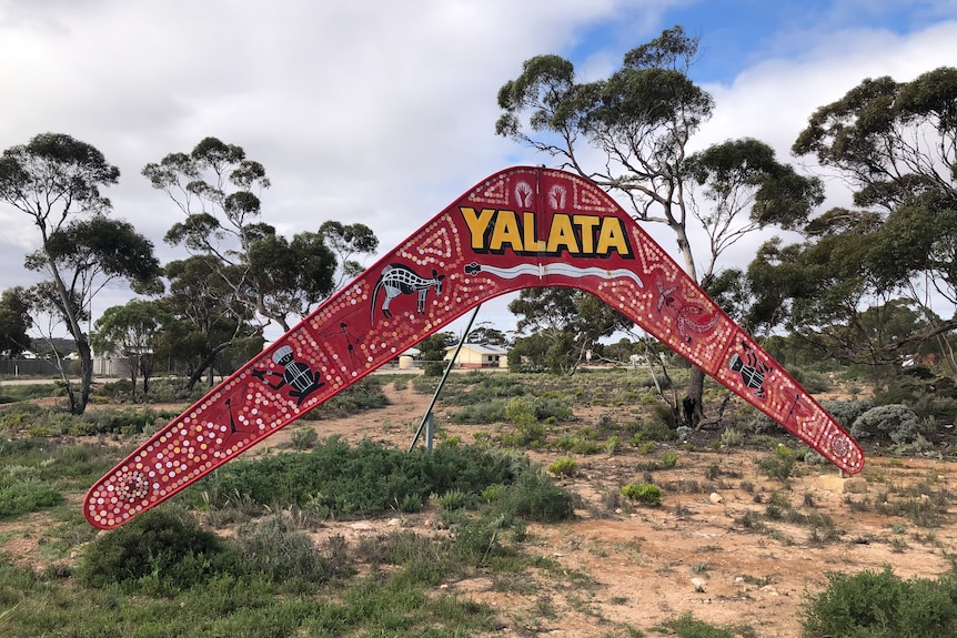 Large boomerang-shaped town entrance sign with Indigenous dot artwork and Yalata at top in yellow letters