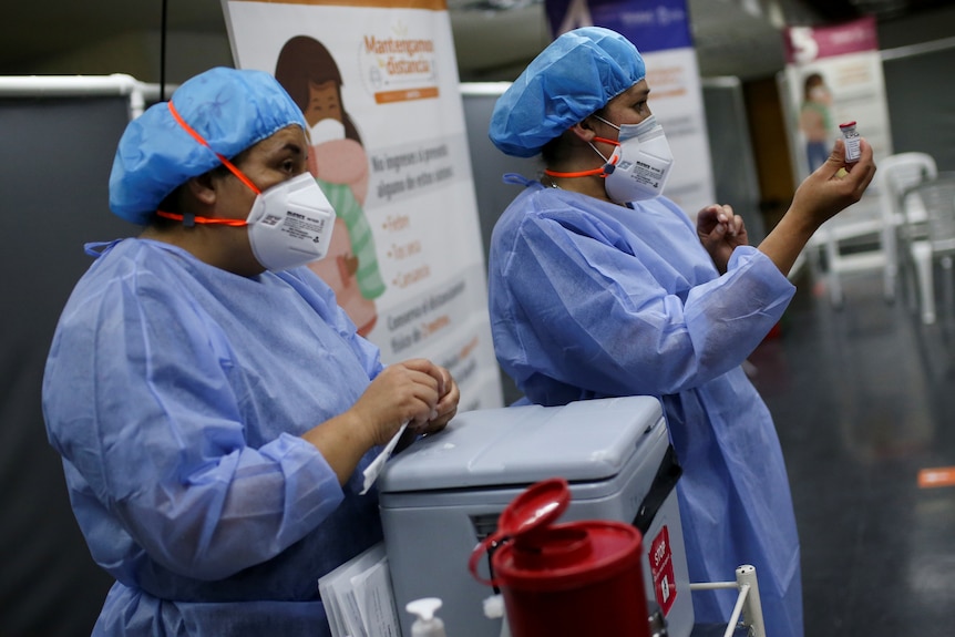 Nurses in PPE prepare doses of the vaccine.
