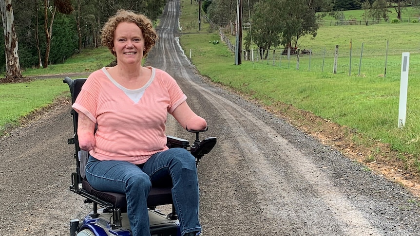 Mandy McCracken sits in a wheelchair at the end of a long dirt road