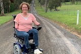 Mandy McCracken sits in a wheelchair at the end of a long dirt road