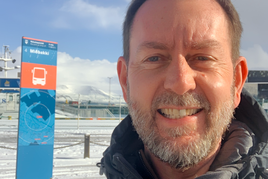A selfie taken by a smiling man with a snowy background.