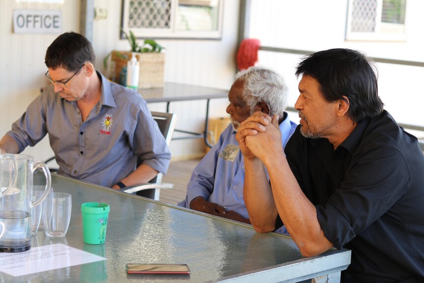 Three men in a meeting.