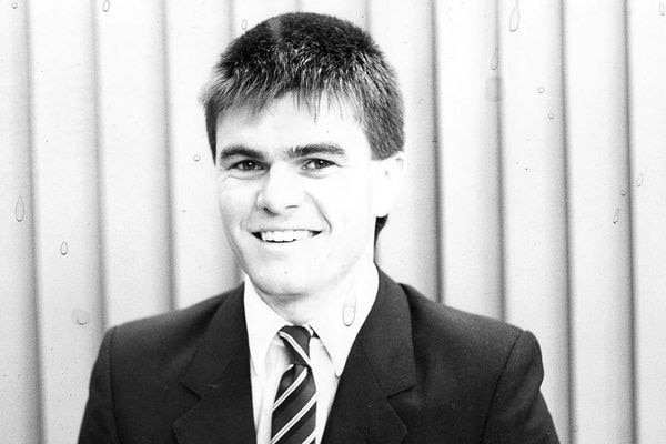 A black and white photo of young man smiling in a suit.