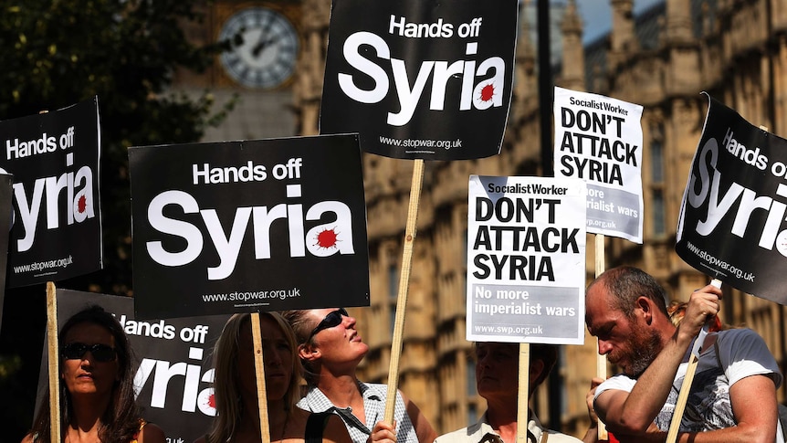 Demonstrators hold placards outside the Houses of Parliament in London on August 29, 2013.